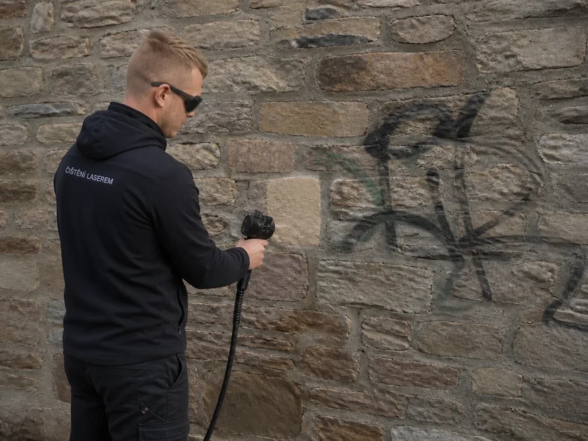 Technik Ekologického čištění odstraňuje graffiti z kamenné zdi laserem
