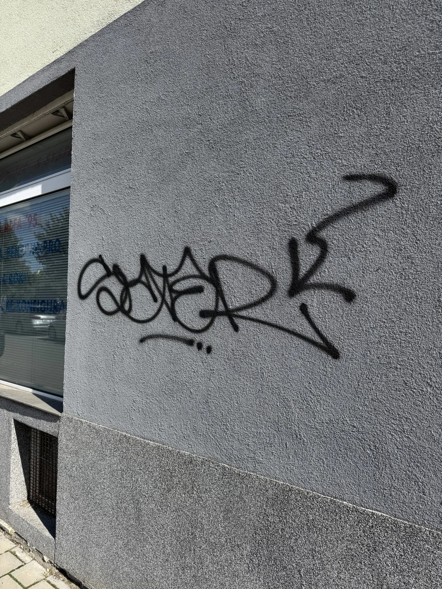 Šedá fasáda s graffiti před čištěním